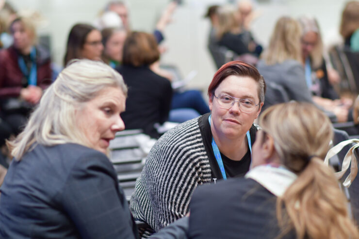 Människor på en konferens. Sitter i ett rum och diskuterar.