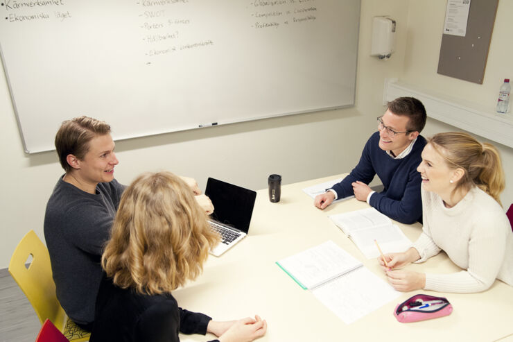 Four young people sit around a table with a computer