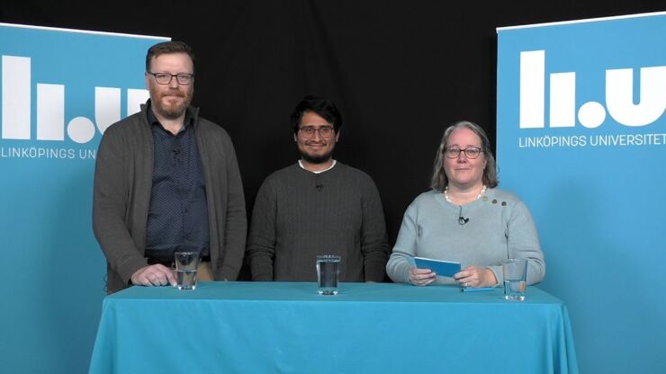 Two men and a woman standing behind a table with blue tablecloth