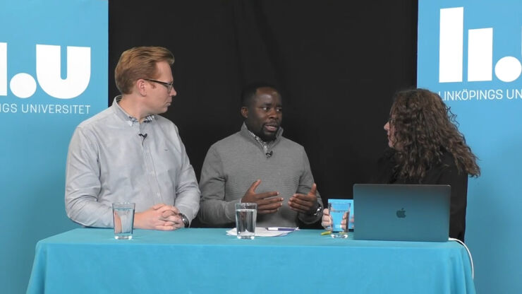 Two men and a woman standing at a table with blue tablecloth