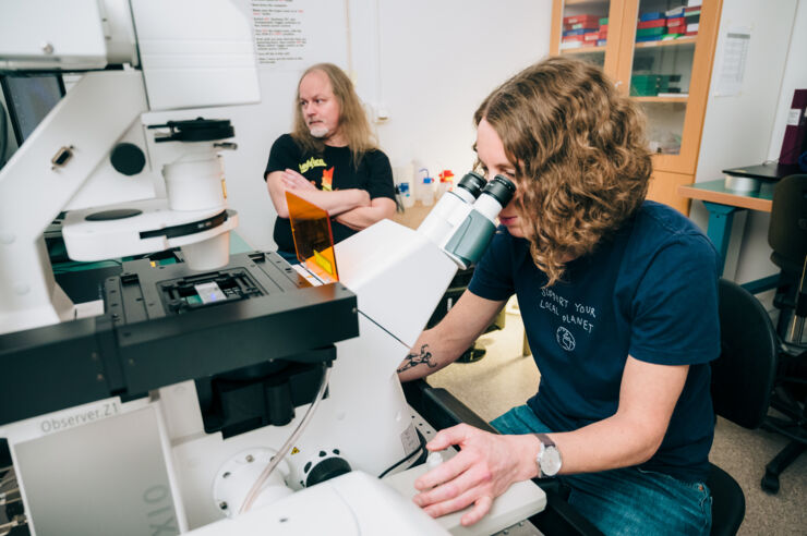 Two researchers by a microscope.