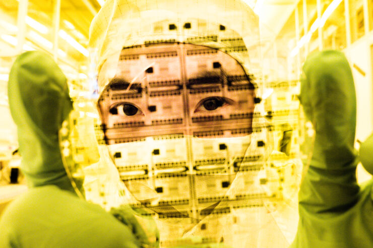 Man i heltäckande labbkläder håller upp en transparent skiva framför ansiktet.