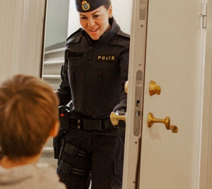 Polis öppnar en dörr, barn i förgrunden