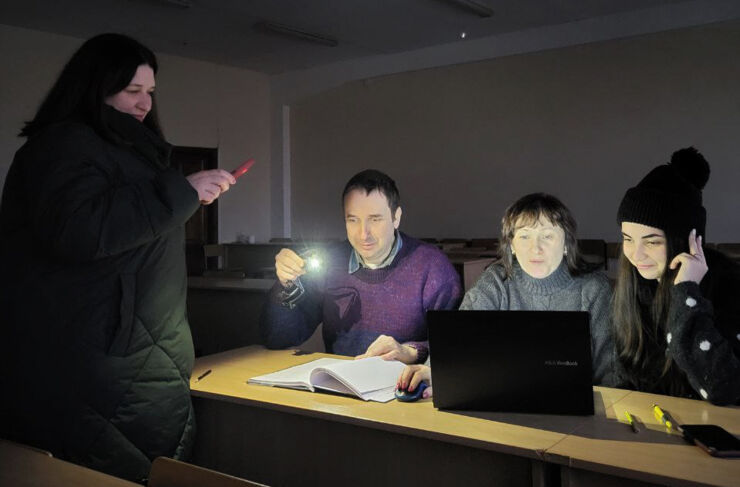 Students in Ukraine that are studying in the light of a flash light during blackout.