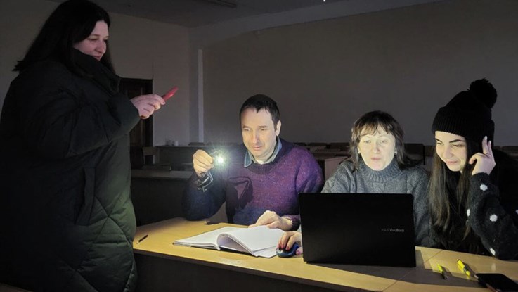 Studenter i Ukraina som studerar i ljuset av en ficklampa vid ett strömavbrtt.