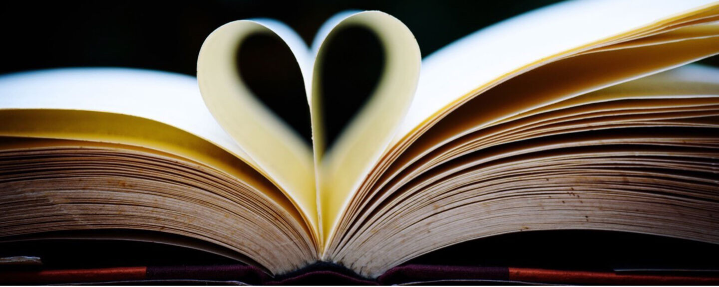 A book that is open, one of the pages has been shaped into a heart.
