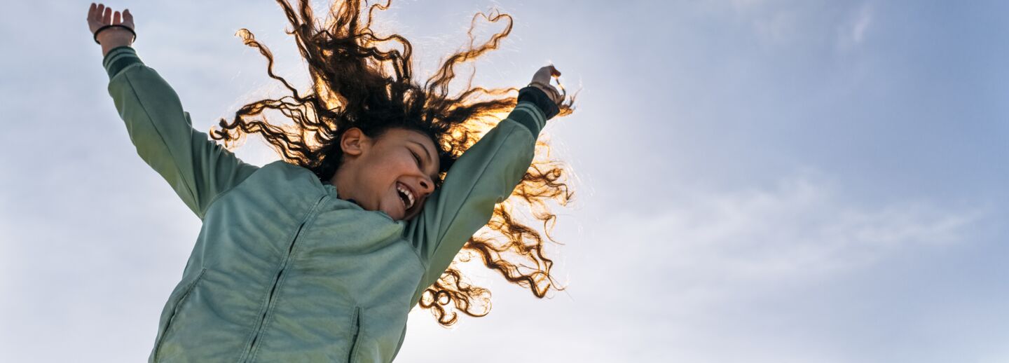 Glad flicka som hoppar så att håret flyger