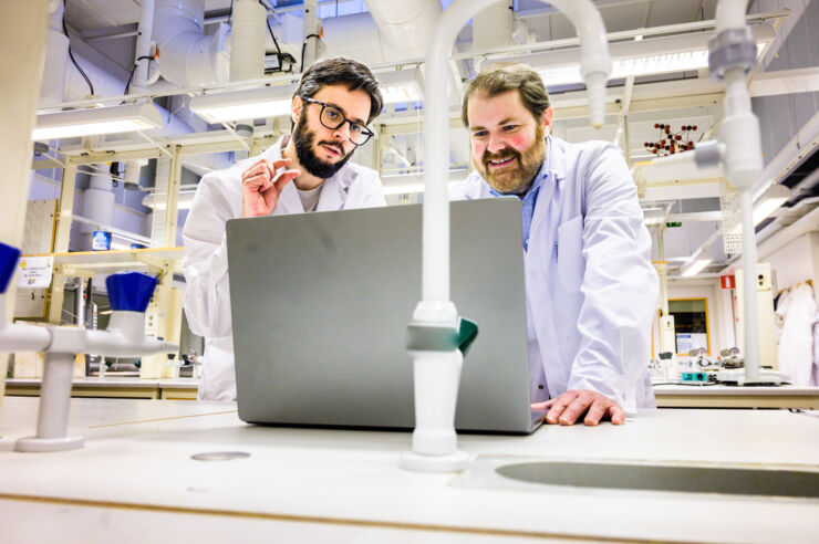 Two men wearing white lab coats in a lab.