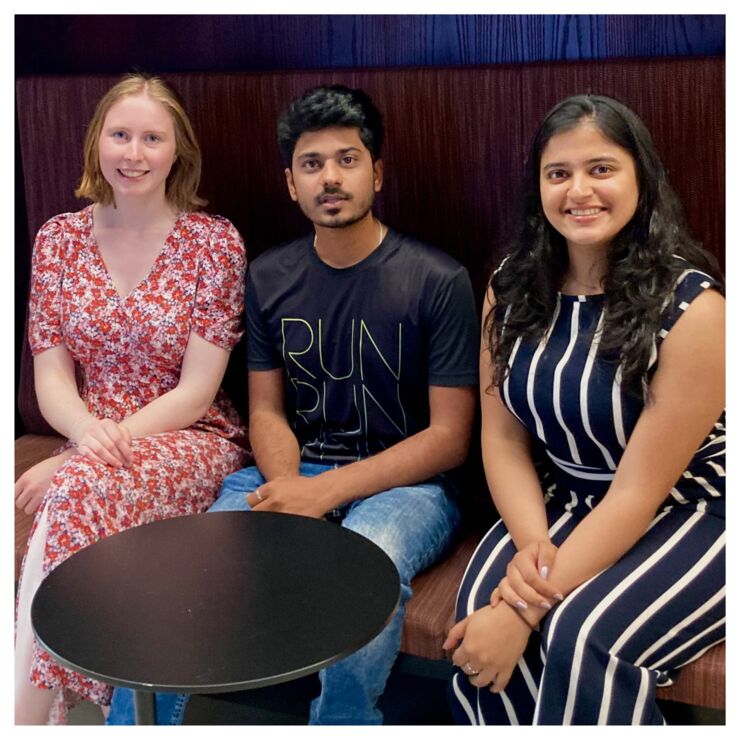 Three persons sitting on a bench and looking into the camera.