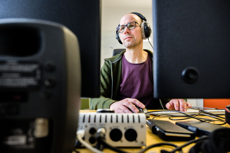 A person with earphones next to a computer. 