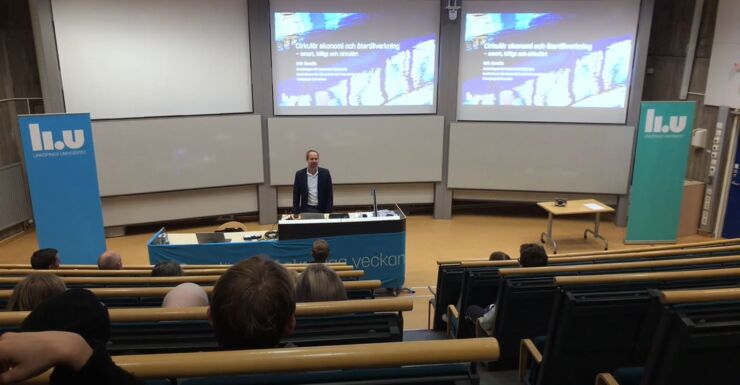 En man föreläser i stor föreläsningssal. 