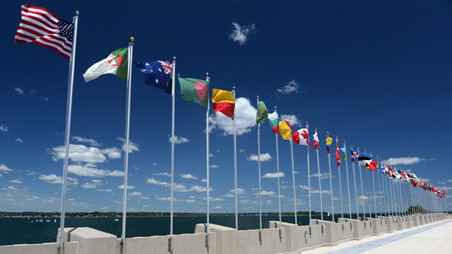 Olika nationsflaggor längs en kaj mot blå himmel med små lätta moln