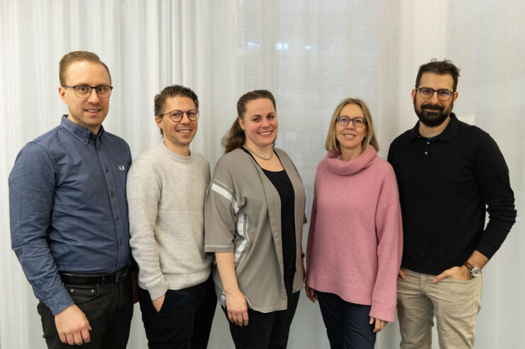 Group image of five people in front a curtain.