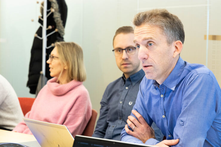 Person talking in the foreground in front of two other people.