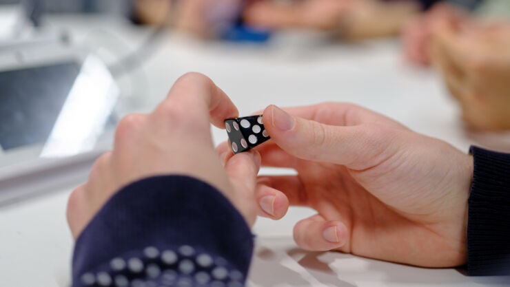 A pair of hands holding a dice.