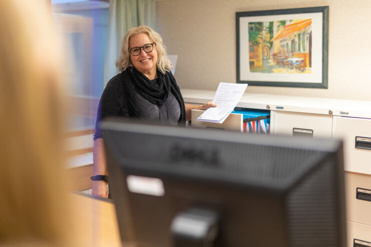 A woman in the student office is holding up a document 