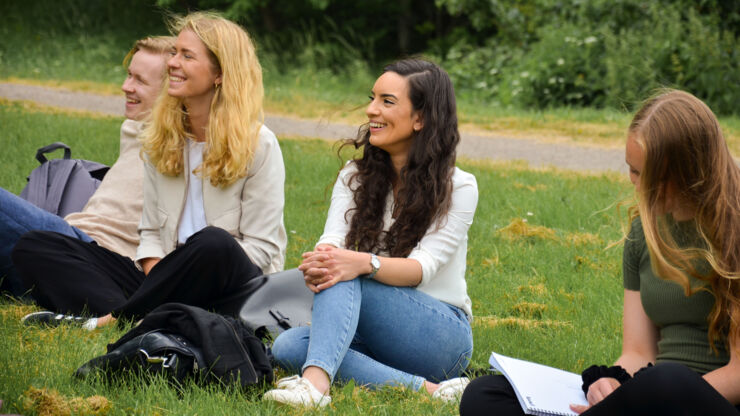 Studenter sitter på gräsmatta.