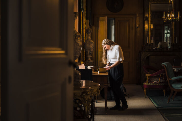 Bild inifrån ett gammalt slottsbibliotek där en kvinna står och läser.