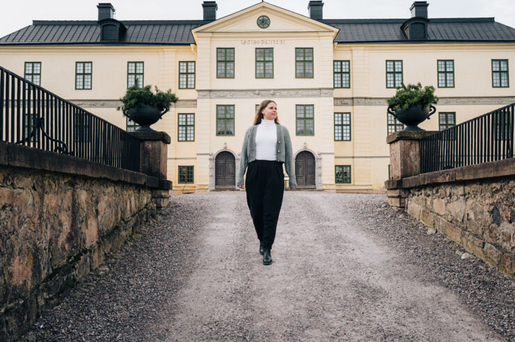 Woman walking in front of a big yellow stone building.