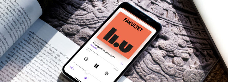Mobiltelefon ligger på ett bord och visar podden Fakultet på skärmen.