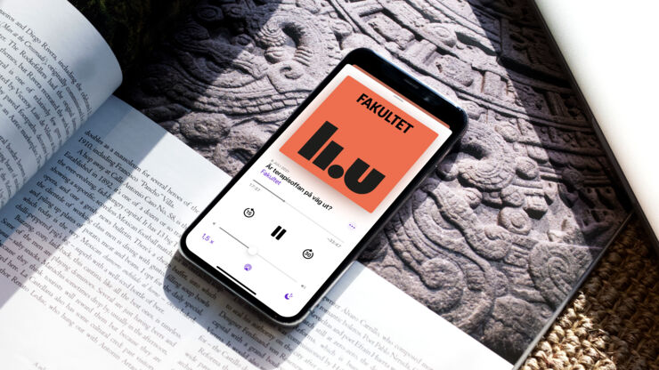 Mobiltelefon ligger på ett bord och visar podden Fakultet på skärmen.