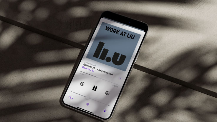 Mobiltelefon ligger på ett stengolv och visar podcasten Work at LiU på skärmen.