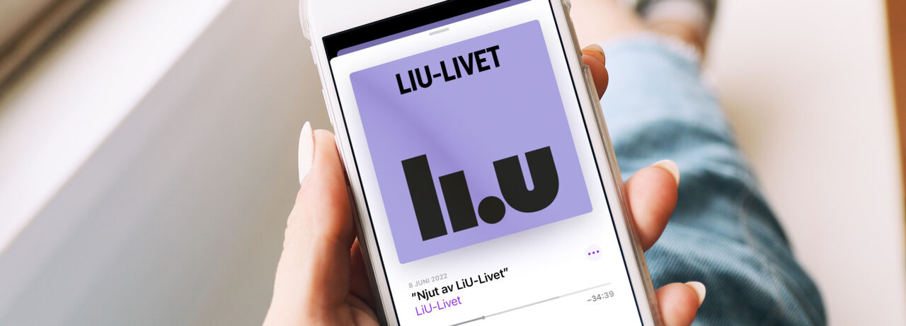 Person sitter i ett fönster och håller upp mobiltelefon som visar podcasten LiU-Livet på skärmen.