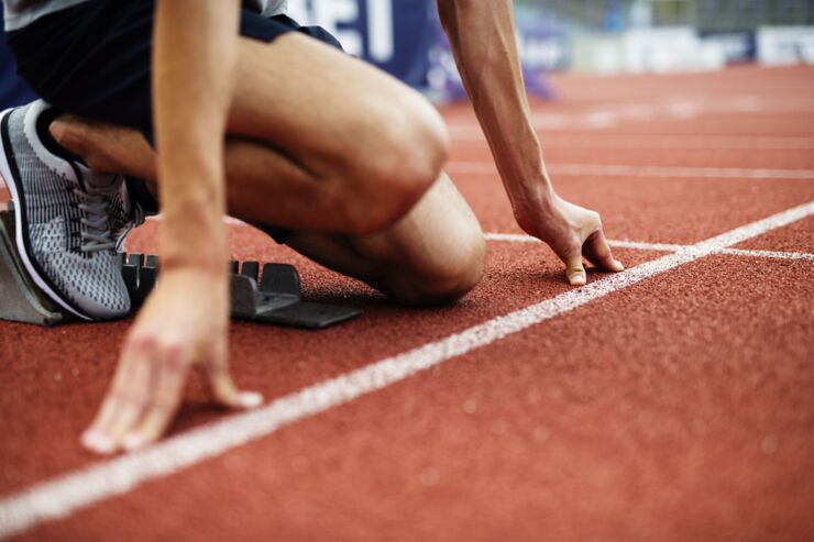 Person in starting blocks on running track.