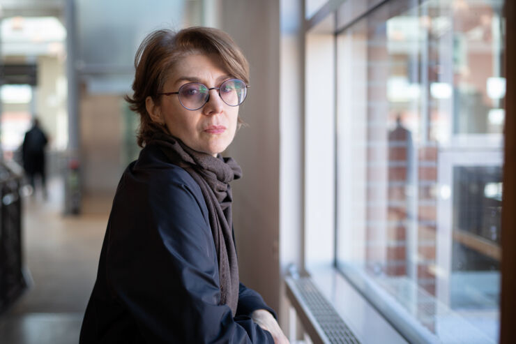 Portrait of a woman standing by a window looking into the camera.