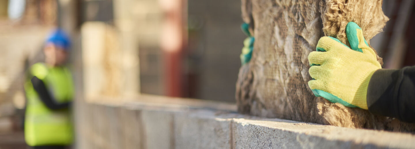 A close up photo on a hand in a glove building a house.