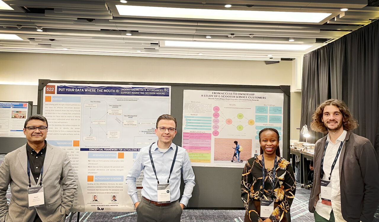 Tre män och en kvinna på konferens.