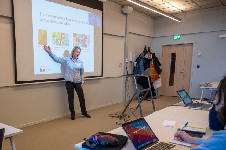 A woman stands in front of people and presents her research.