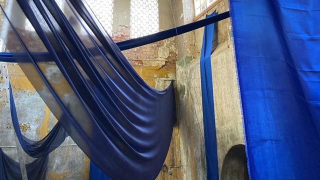 Bild på ett konstverk där blått tyg hänger på olika nivåer i en gammal turbinhall.