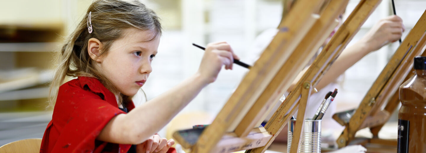 Ett barn sitter och målar med oljefärg