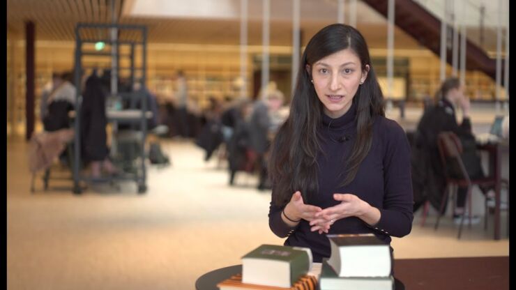 Dark-haired young woman standing at round table with books