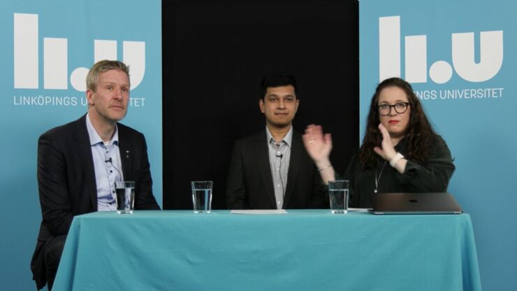 Three people sitting at table with blue tablecloth