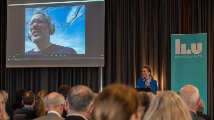 A man on a screen in front of an audience