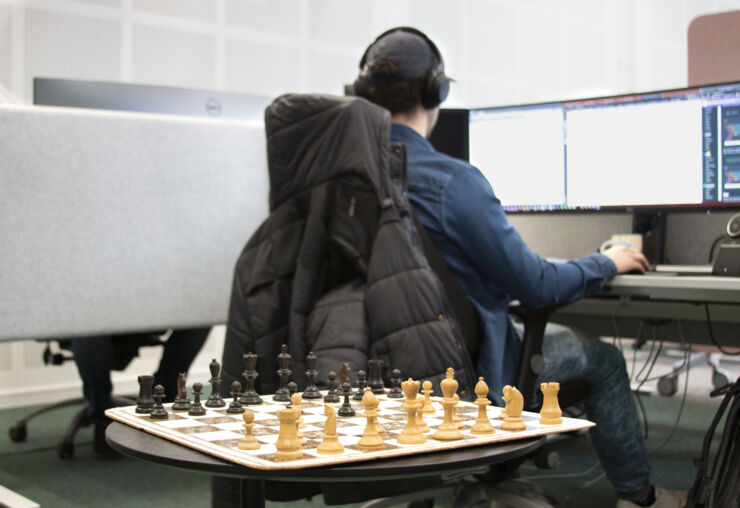 Schackbräde står uppställt på ett kontor. En medarbetare sitter vid sin dator och arbetar med ryggen mot betraktaren.
