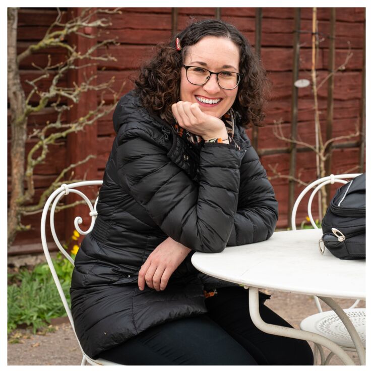 The podcast guest Sarah Mitchell sitting at a table outside and smiling at the camera.