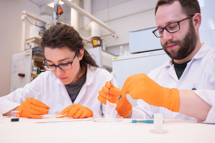 Tw researchers in an lab sitting at a table.