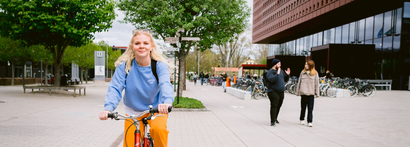 Kvinnlig student som cyklar på Campus Valla