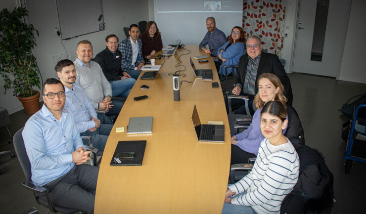 Group of researchers, entreprenours and others by meeting table.