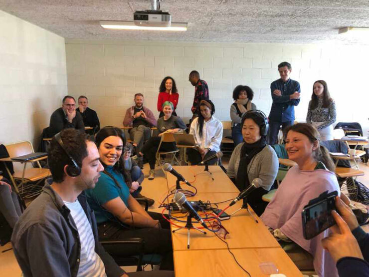 Picture of students sitting around a table recording a pod cast. 