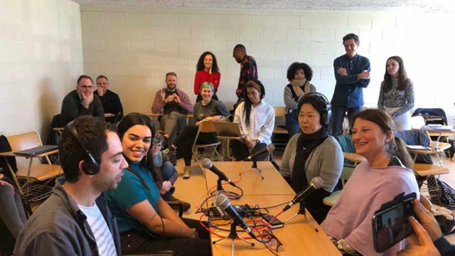 Picture of students sitting around a table recording a pod cast. 