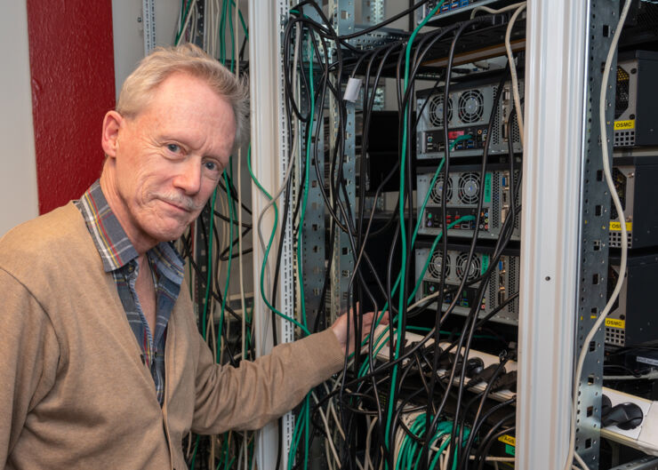 Man framför serverrack med sladdar