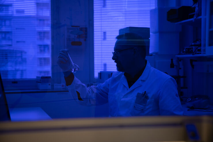 Manlig forskare i labbmiljö med blå bakgrund.