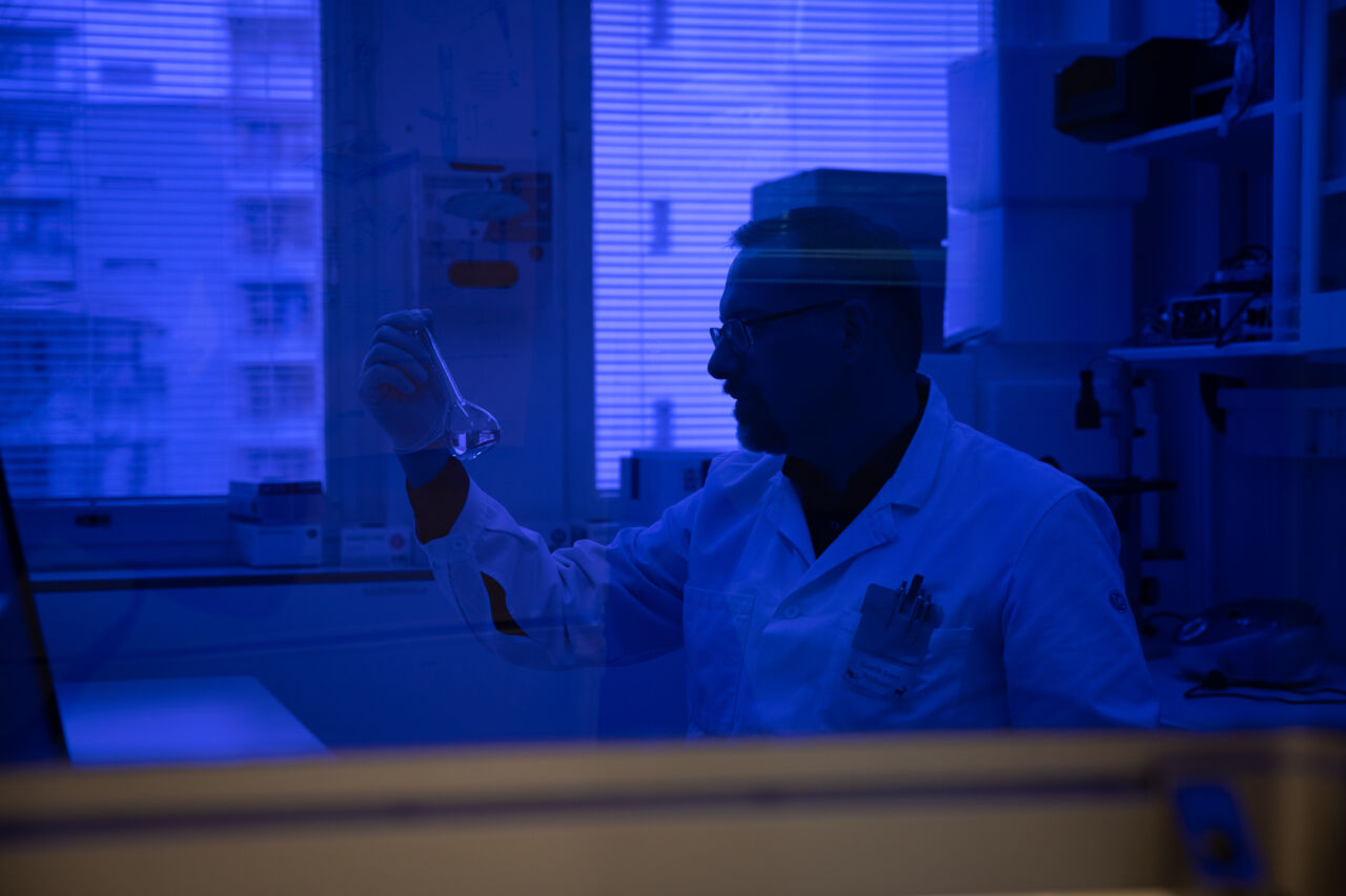 Male researcher in lab, blue background light.