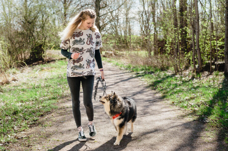 Ung kvinna promenerar med hund utomhus