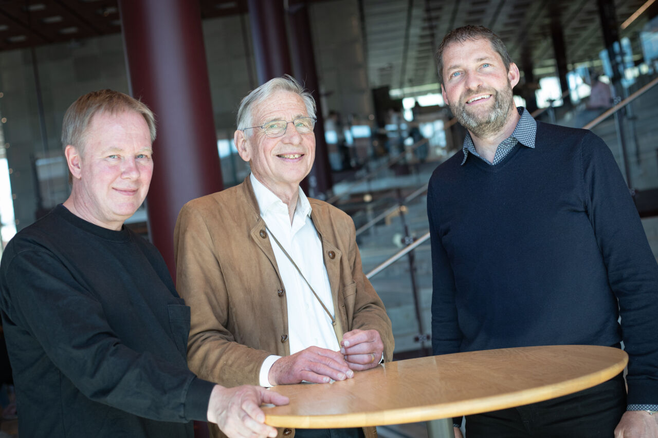 Tre personer står vid ett bord