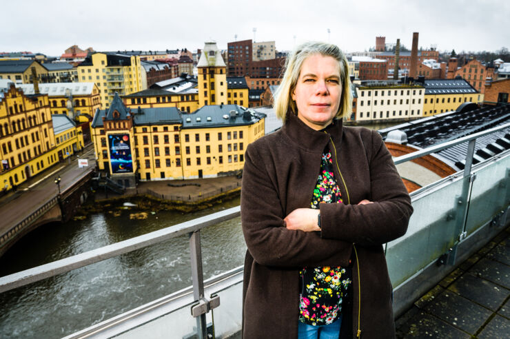 Person (Anna Fredriksson) stands on a roof with the city as a backdrop. 
